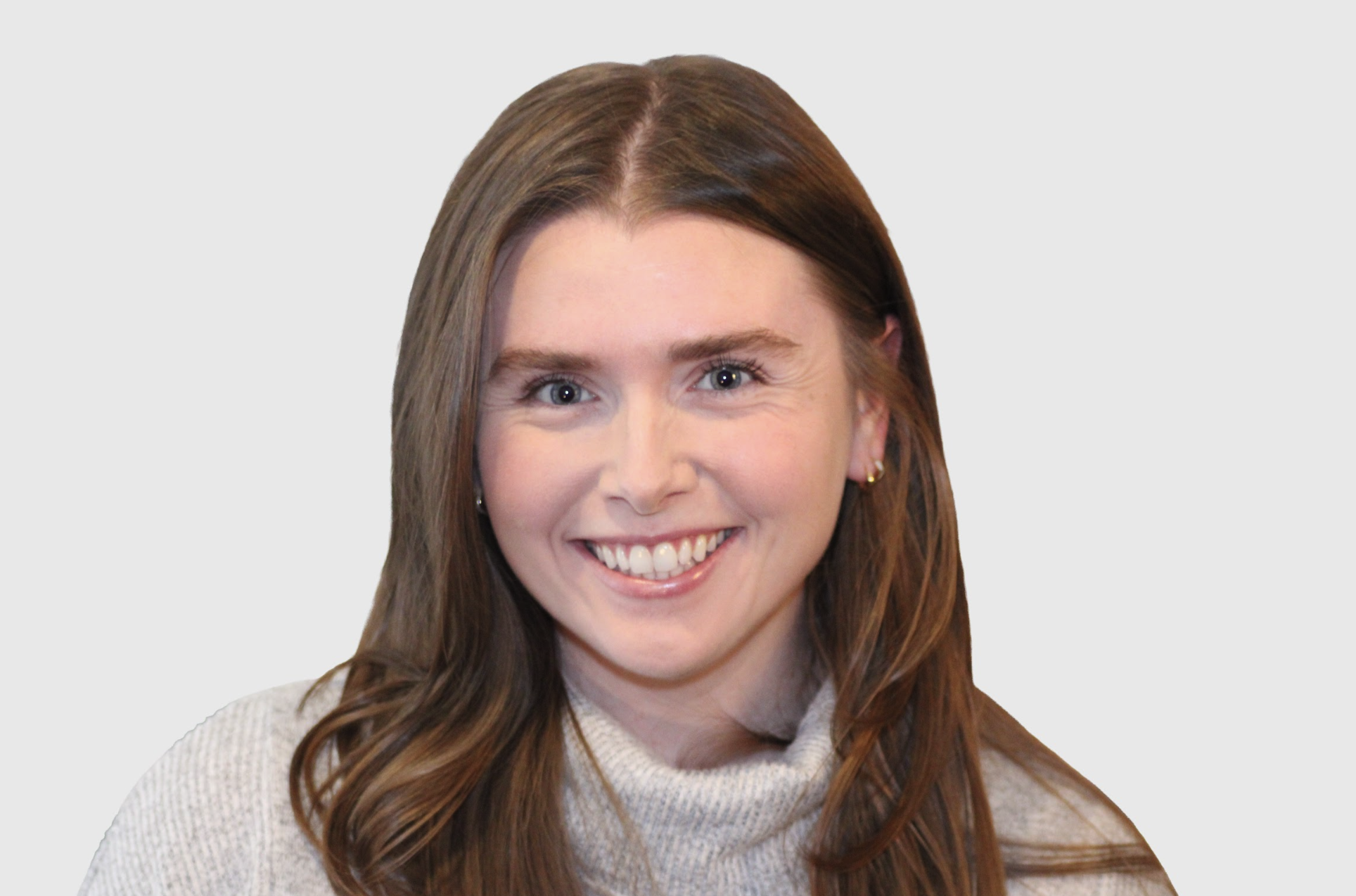 Claire Savage, white female therapist with brownish-reddish hair and blue eyes, smiling and showing teeth with earrings.