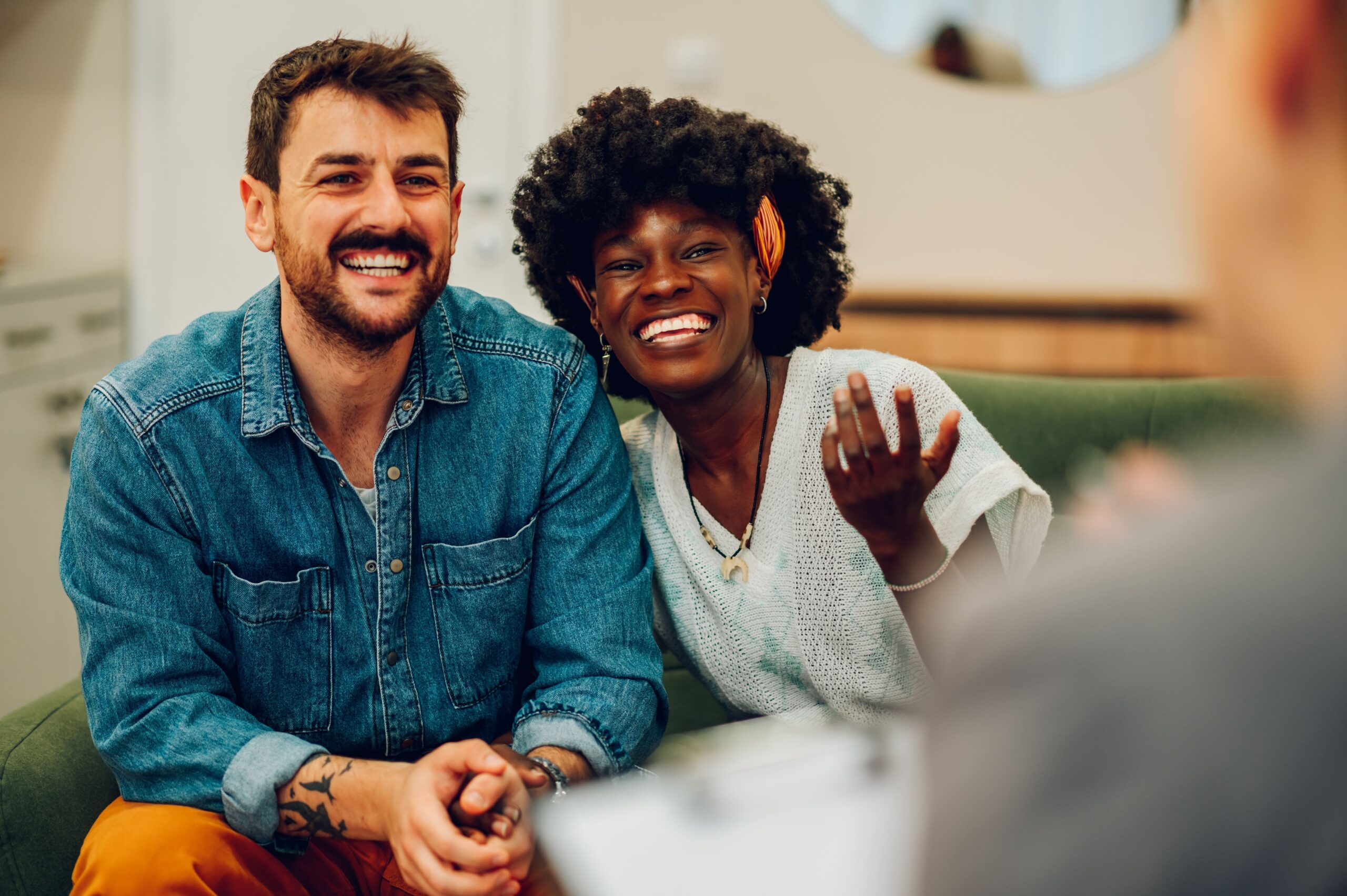 Smiling couple sitting together and talking with another person in a casual setting