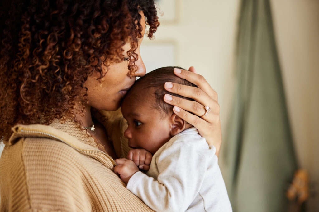 Mother holding and kissing her baby’s head, showing love and care