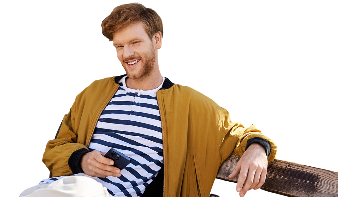 Smiling man in striped shirt and yellow jacket sitting with phone in hand