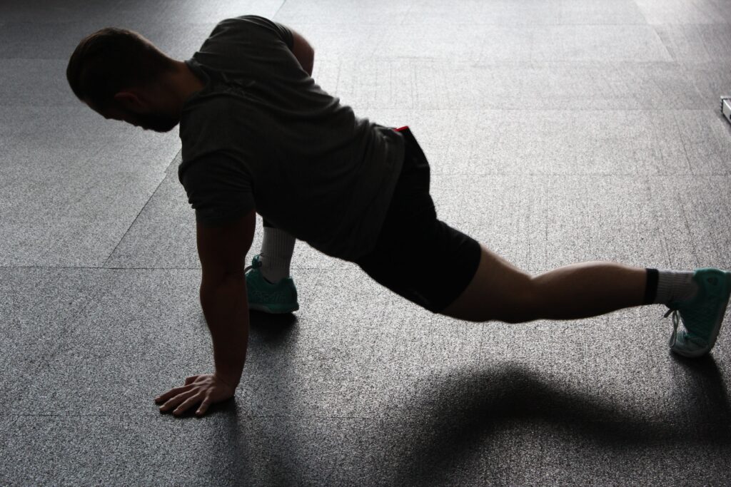 A person performing a stretching exercise in a gym, focusing on strength, flexibility, and physical well-being