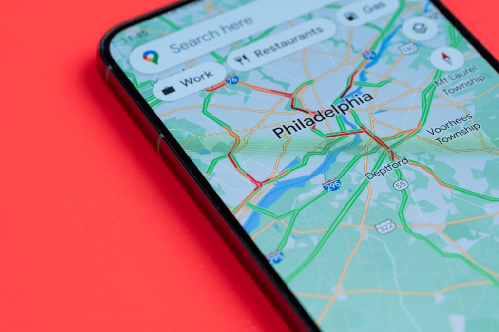 Smartphone displaying a digital map of Philadelphia with highlighted traffic routes on a red background